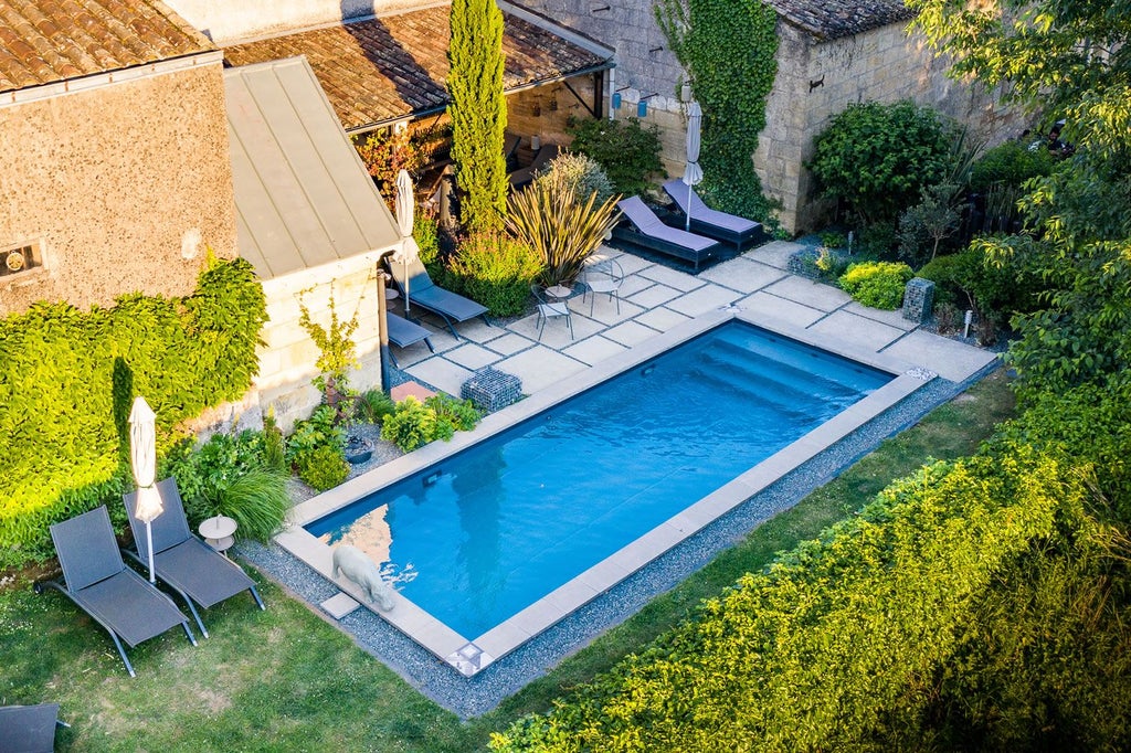 Elegant French countryside hotel with stone facade, manicured gardens, and lush vineyards, showcasing rustic luxury and scenic Burgundy landscape at dusk