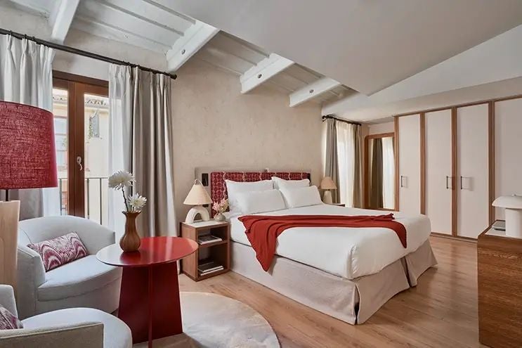 Elegant stone-walled boutique hotel room in Mallorca with plush white bedding, rustic wooden furniture, and soft ambient lighting