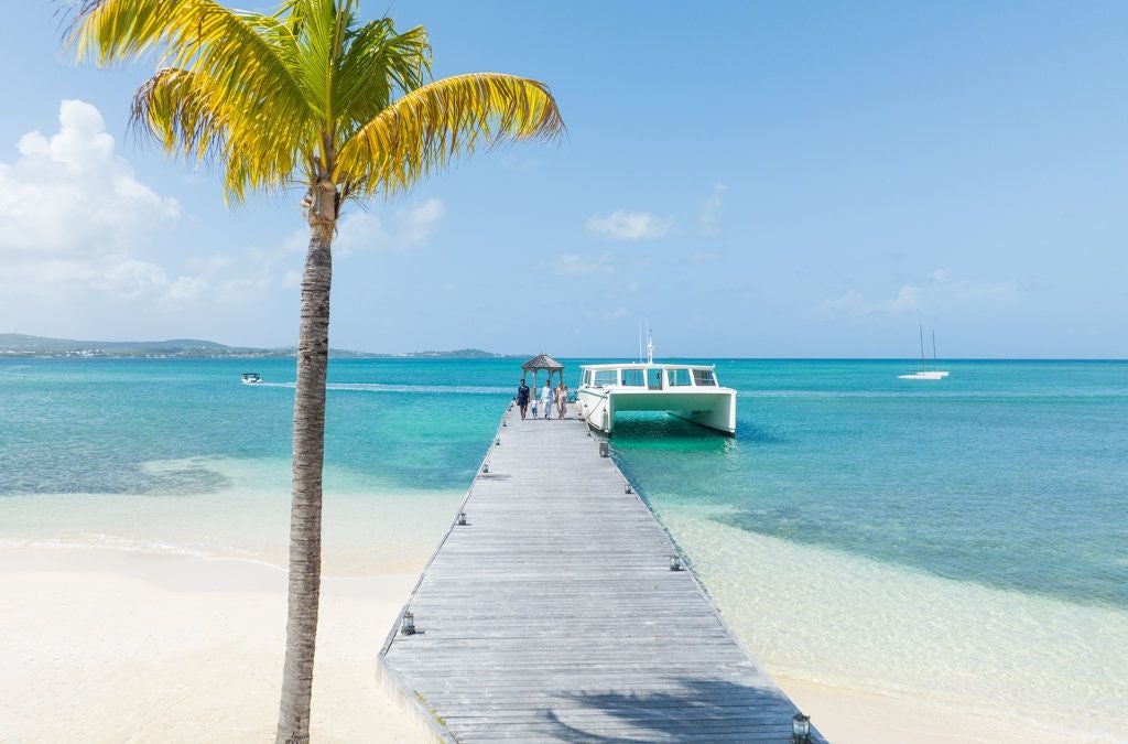 Luxurious beachfront resort with pristine white sand, turquoise Caribbean waters, and elegant palm-lined grounds of an exclusive private island retreat