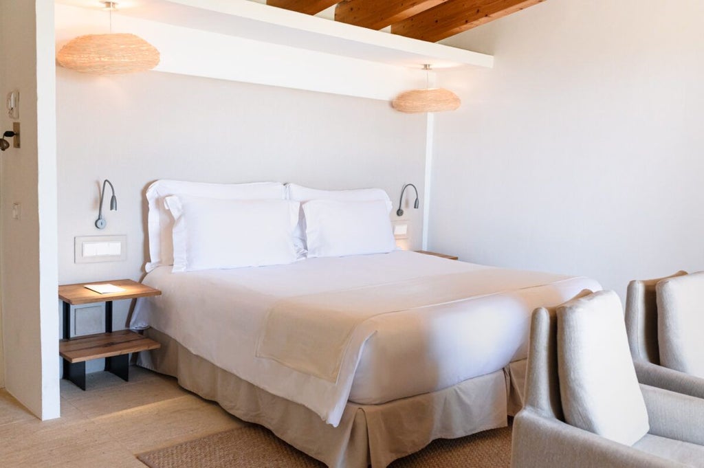 Elegant Mediterranean stone-walled hotel room with sweeping blue sea view, white linens, minimalist design, and natural light streaming across rustic luxury accommodation