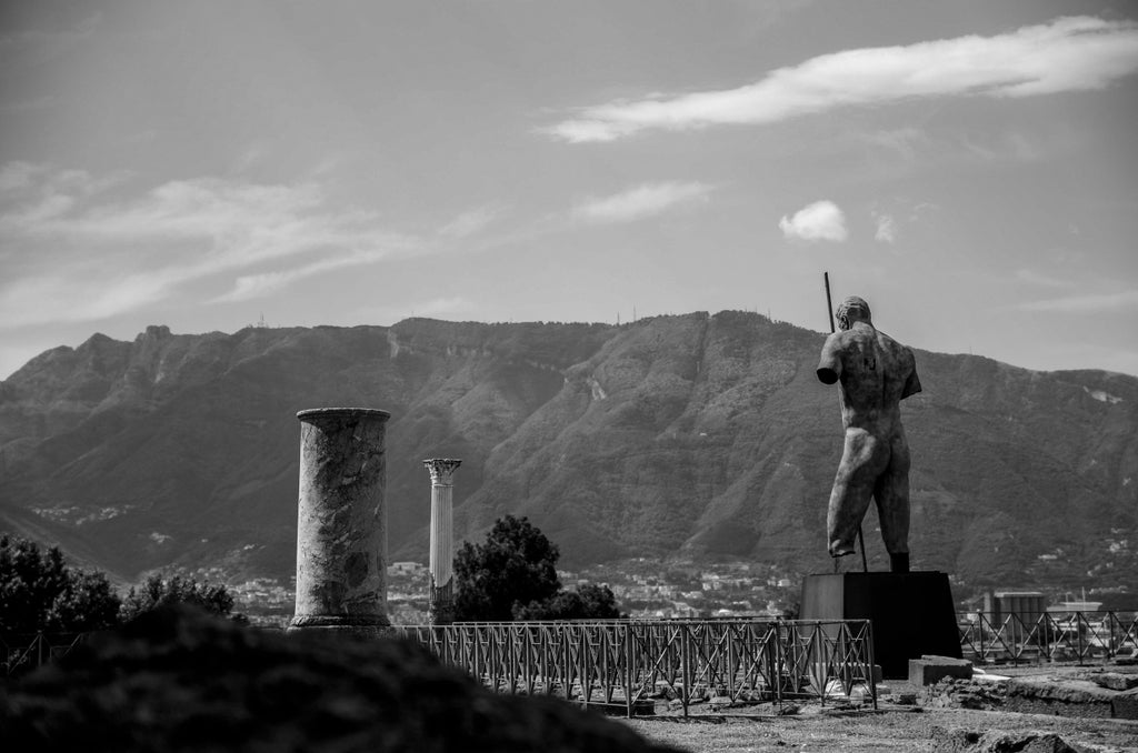 Ancient ruins of Pompeii showcasing preserved Roman columns and stone pathways against Mount Vesuvius with tour guides leading visitors