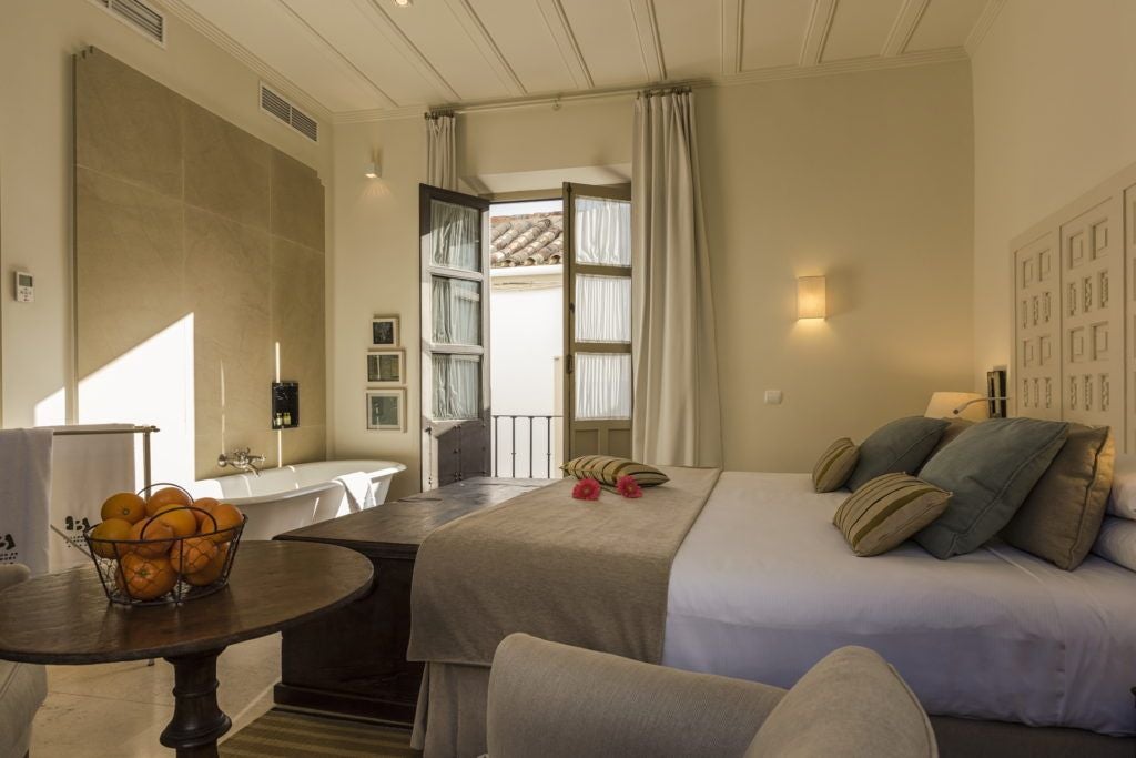 Elegant Spanish colonial-style hotel room with ornate wooden furniture, arched windows, and soft sunlight illuminating traditional architectural details