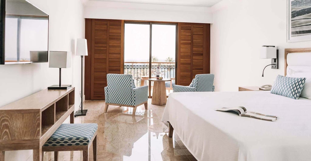 Luxurious panoramic sea view room at coastal hotel, featuring modern decor, plush king bed, and expansive floor-to-ceiling windows overlooking azure Mediterranean waters