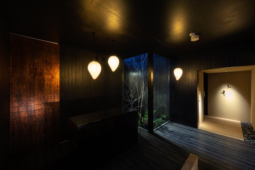 Traditional Japanese luxury hotel exterior featuring stone path, lantern lighting, wooden sliding doors and manicured garden landscaping