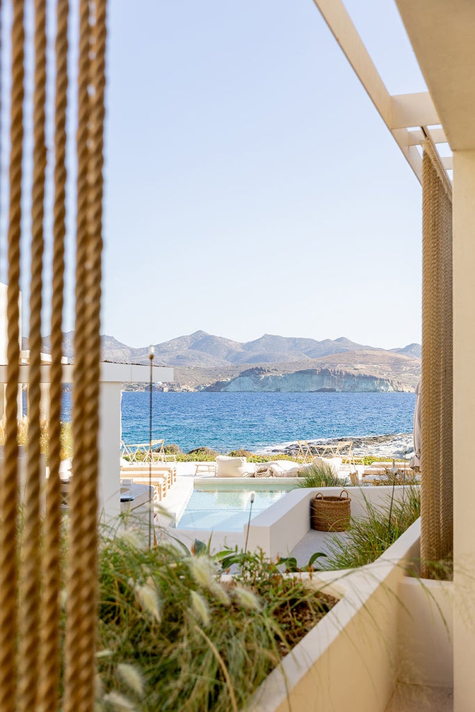 Modern white-washed cliffside suite with private infinity pool overlooking the Aegean Sea and Santorini's caldera at sunset