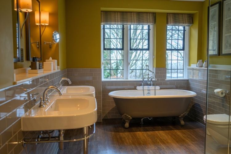 Elegant oak-paneled bedroom with plush king bed, antique wooden furniture, and soft natural light in luxurious Cotswolds countryside manor house