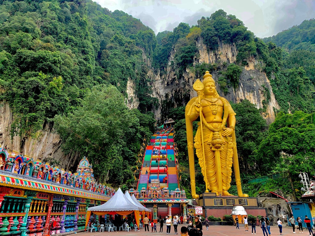 Steep limestone staircase leading to grand Hindu temple entrance at Batu Caves, colorful steps ascending against dramatic rock formation near Kuala Lumpur, Malaysia