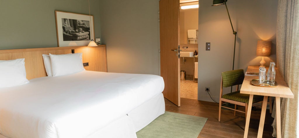 Elegant French prestige room at Les Sources de Cheverny, featuring plush white bedding, rich wooden furniture, and soft natural lighting