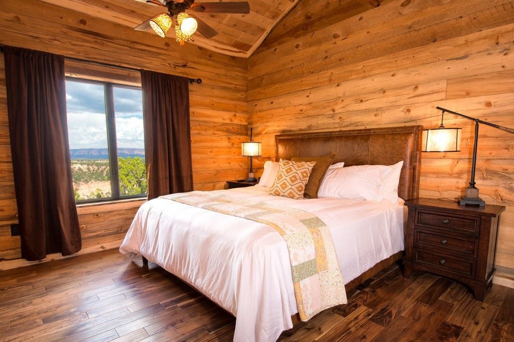 Rustic wooden lodge room with plush bedding, panoramic mountain views, and warm earth-toned decor at a scenic ranch accommodation near scenset National Park