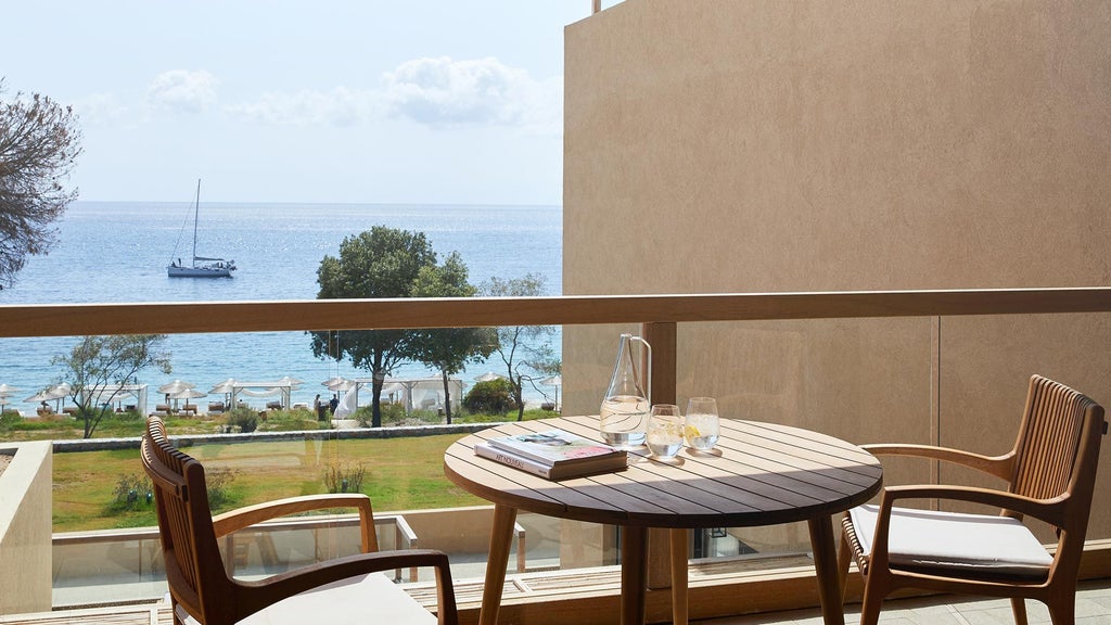 Luxurious double supreme deluxe hotel room at ELIVI Skiathos, featuring elegant white decor, crisp linens, and panoramic sea view through floor-to-ceiling windows