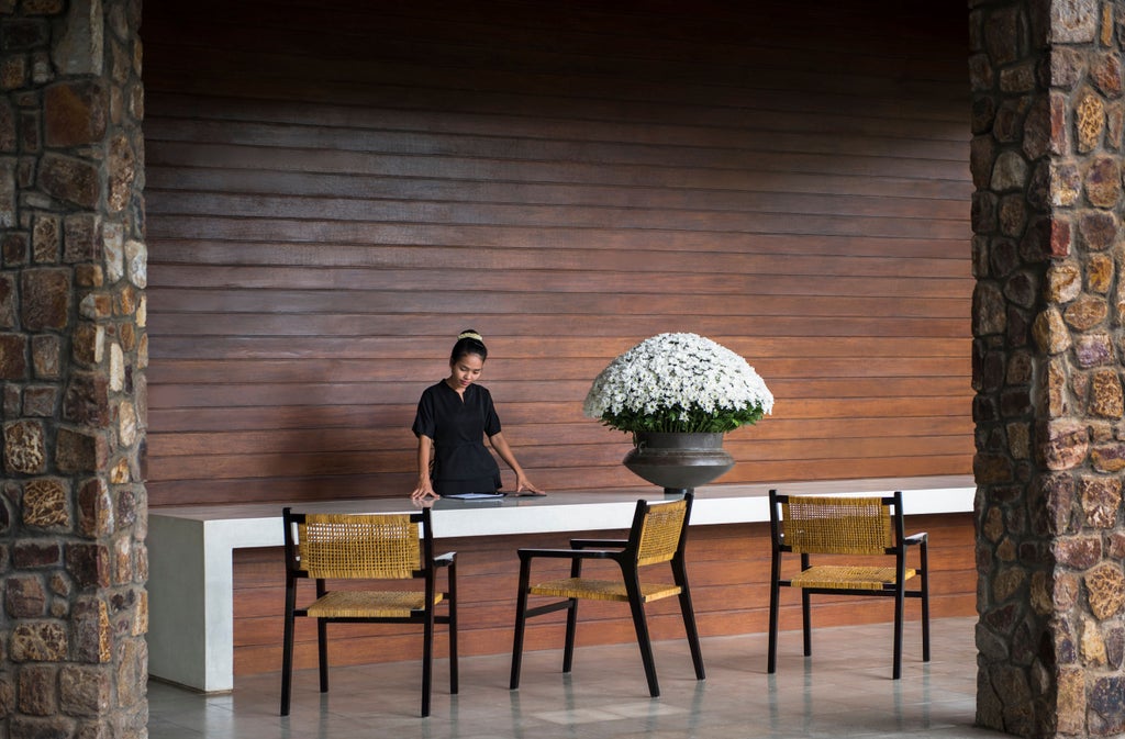 Serene luxury hotel courtyard with reflecting pool surrounded by stone walkways and tropical landscaping at Amansara resort, Cambodia