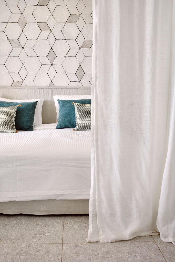 Luxurious Deluxe Suite with elegant white and blue decor, featuring a spacious king bed, contemporary furnishings, and panoramic view of Cretan coastline