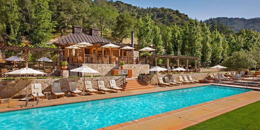 Elegant outdoor stone lodge at sunset with panoramic mountain views, glowing warm lights, and a tranquil reflection pool