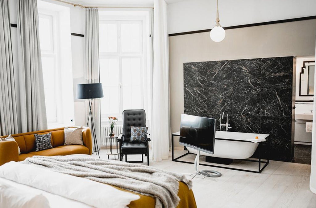 Elegant boutique hotel room featuring red velvet furnishings, ornate gold mirrors, and crystal chandeliers in classic Viennese style