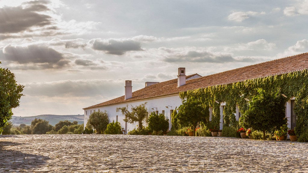 Whitewashed luxury Portuguese manor hotel with terracotta roof and manicured grounds set against rolling countryside at golden hour