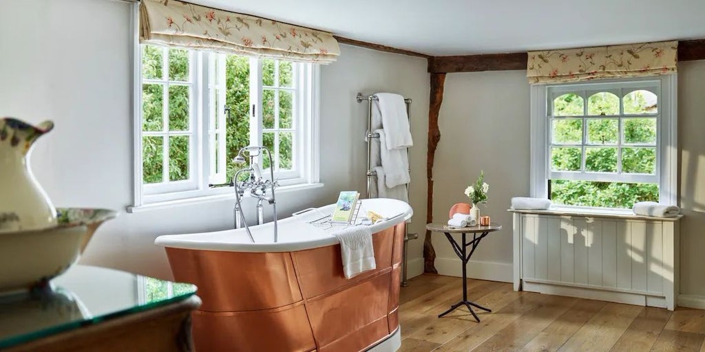 Elegant Dower House bedroom at Coworth Park with plush white bedding, antique furnishings, soft neutral tones, and large windows overlooking manicured gardens