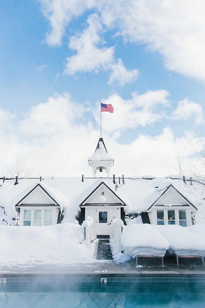 Elegant boutique hotel exterior with historic stone facade, pristine white windows, and manicured landscaping in a picturesque United States setting