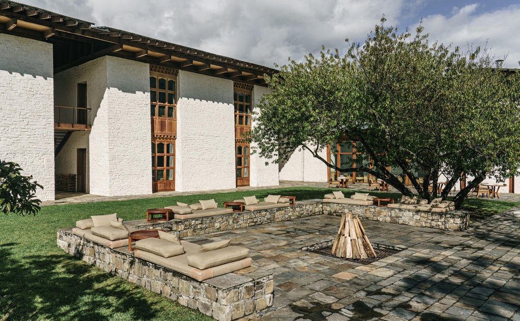 Traditional Bhutanese lodge with elegant stone and wood facade nestled among pine forests, featuring spacious terraces and mountain views