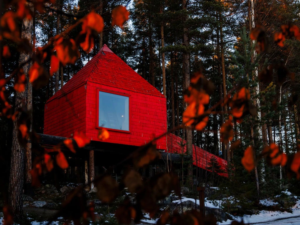 Suspended modern treehouse suite with mirrored exterior reflecting pine forest, blending seamless luxury architecture into pristine Swedish woodland landscape