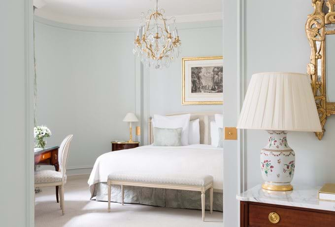 Elegant junior suite with Louis XVI furniture, crystal chandelier, marble fireplace, floor-to-ceiling windows and plush king bed