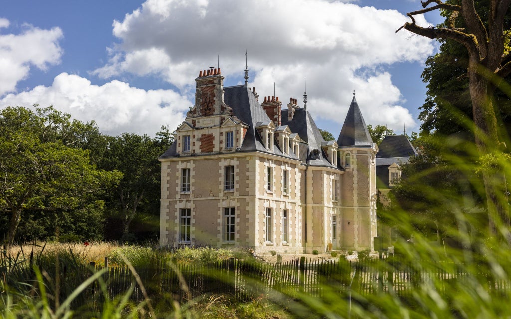 Elegant limestone château hotel nestled in Loire Valley, surrounded by manicured gardens, lavender fields, and soft evening light