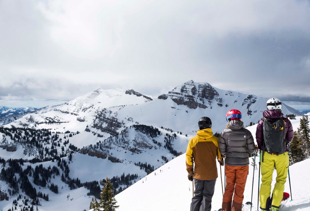 Luxurious Amangani mountain resort featuring stone and wood architecture, infinity pool overlooking snow-capped Grand Teton peaks at sunset