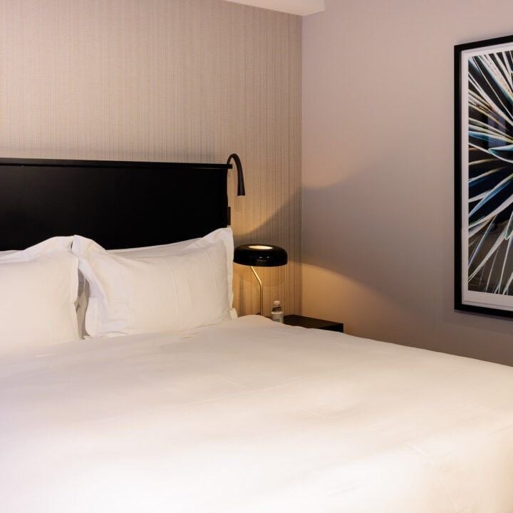 Elegant modern suite with plush white bedding, soft accent pillows, sleek city view, contemporary furnishings in Brussels city center hotel room