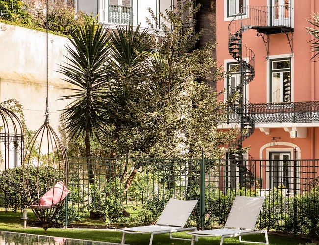 Elegant white palace-style hotel with ornate balconies, towering palm trees and manicured gardens under bright blue Portuguese sky