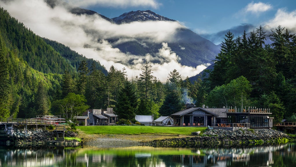 White safari-style luxury tent nestled in pristine Canadian wilderness, surrounded by evergreen forest and misty mountain backdrop