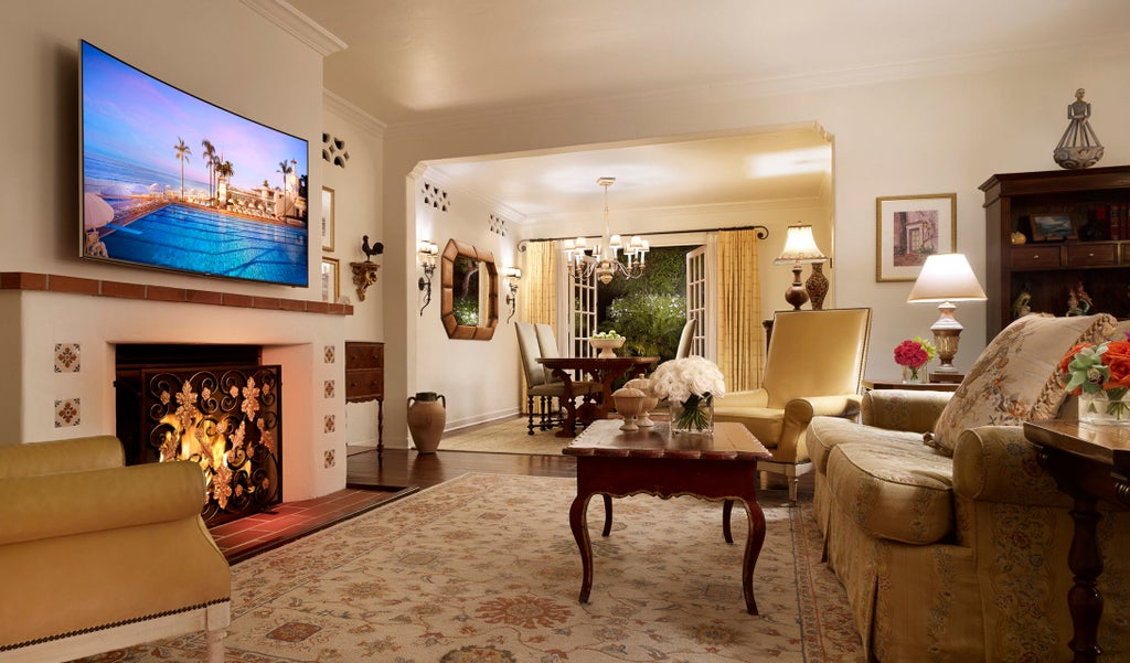 Elegant Spanish Colonial-style luxury hotel with white stucco walls and red-tiled roofs nestled among palm trees along Santa Barbara's coastline