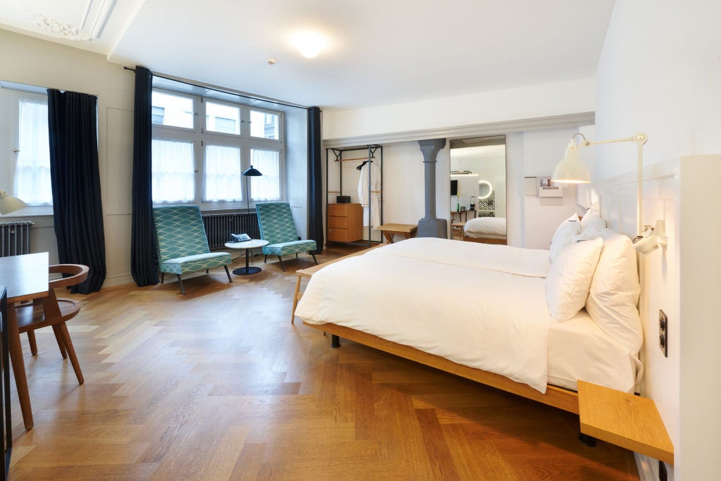 Elegant Swiss hotel room with modern minimalist design, featuring crisp white linens, large windows, and sophisticated neutral color palette overlooking urban scenery