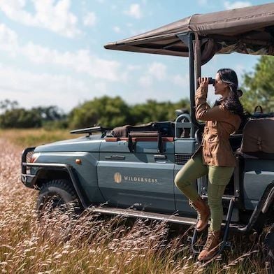 Luxurious safari lodge nestled in the Botswana wilderness, featuring thatched-roof tents, wooden walkways, and sweeping views of the untouched landscape at dusk.