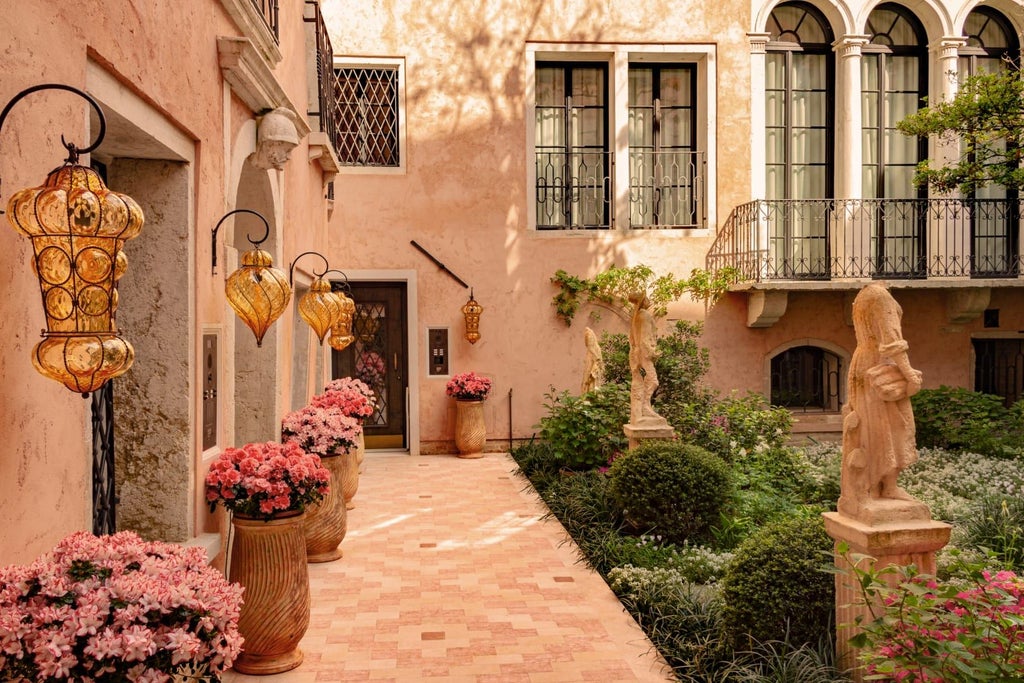 Elegant Renaissance-style luxury hotel facade in Venice, with ornate stone balconies, arched windows, and warm terracotta tones against a soft blue sky