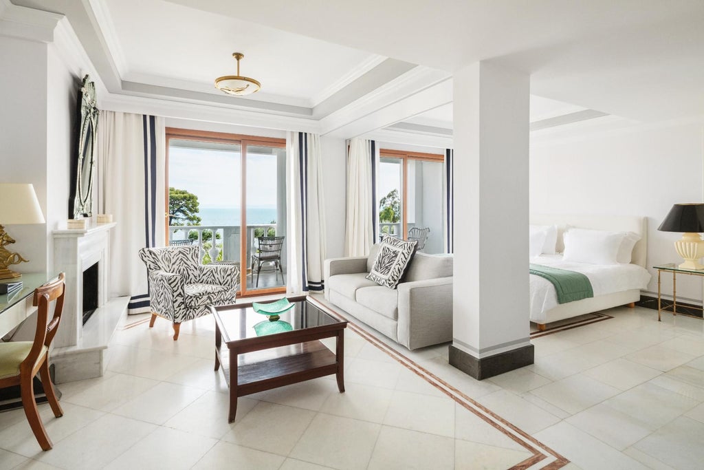 Spacious two-bedroom luxury suite with panoramic sea views, elegant white decor, private balcony, and contemporary Mediterranean design at scenic coastal resort.