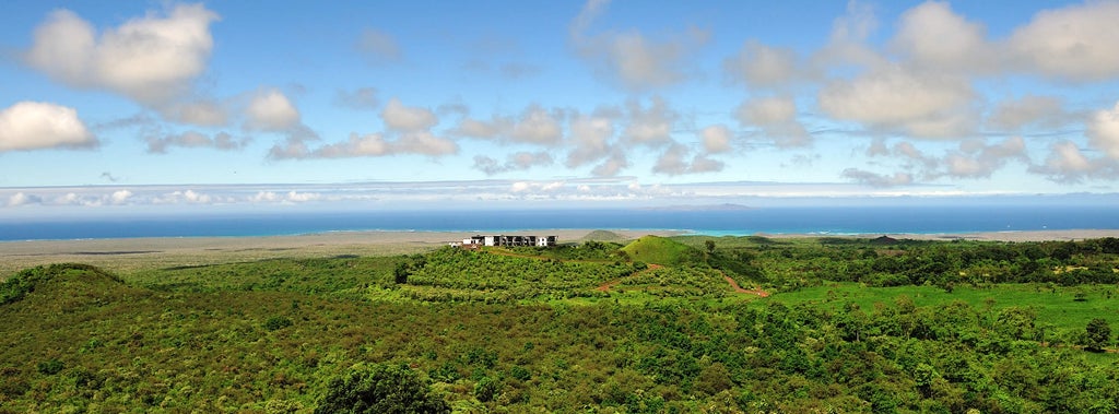 Luxury eco-lodge perched on volcanic terrain, overlooking lush Galapagos landscape with sleek modern architecture blending seamlessly with natural surroundings