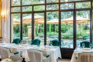 Elegant French countryside villa with stone facade, manicured gardens, and terracotta roof, showcasing luxurious Provençal architecture against lush green landscape