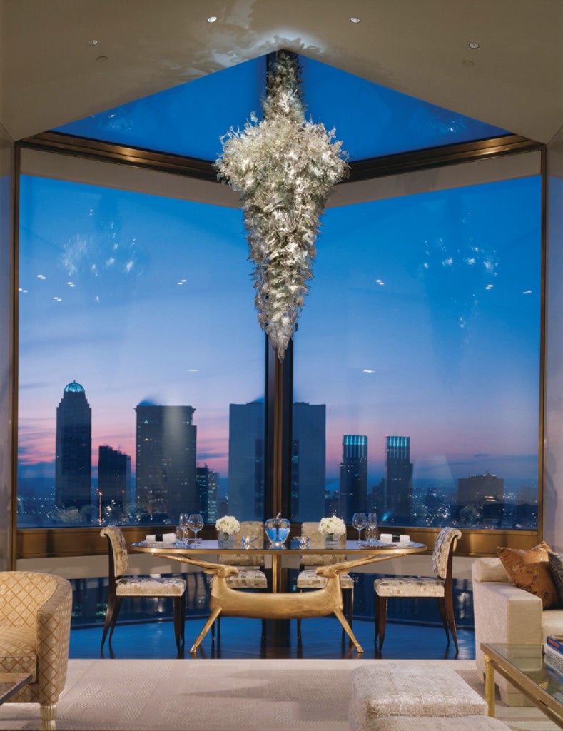 Elegant art deco-style skyscraper hotel with limestone facade and gold accents, rising majestically above Manhattan's bustling streets