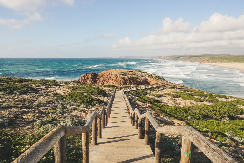 Scenic luxury cliffside views of Algarve's golden coastline with red-tinted rock formations and crystal-clear turquoise waters at sunset