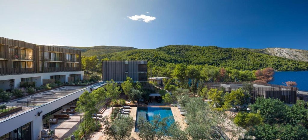 Sleek, contemporary waterfront hotel with infinity pool overlooking the Adriatic Sea, set among olive trees and pine forest at sunset