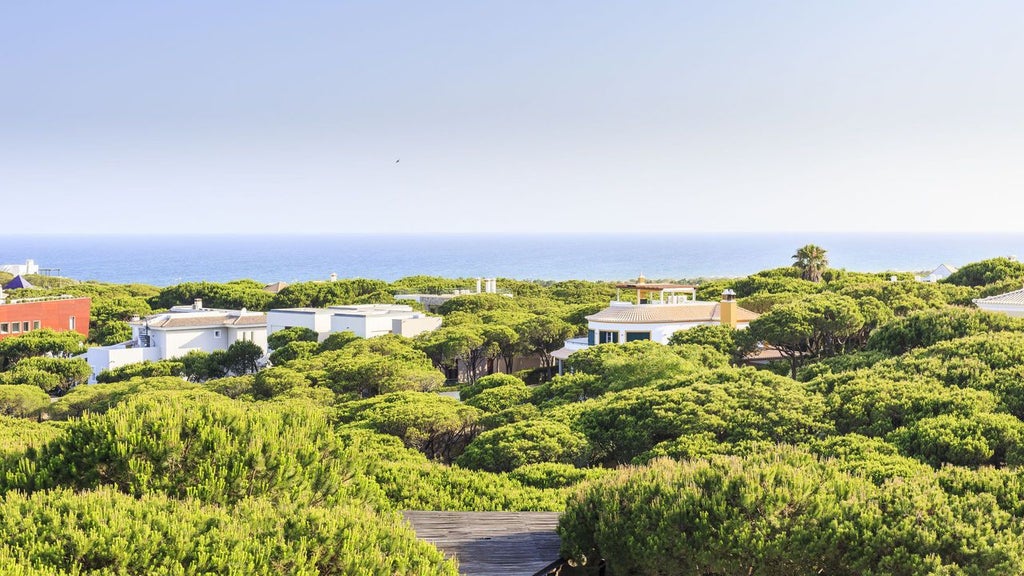 Luxurious white-walled Octant resort nestled among pine trees, with modern minimalist architecture overlooking a pristine coastal landscape in southern Portugal.