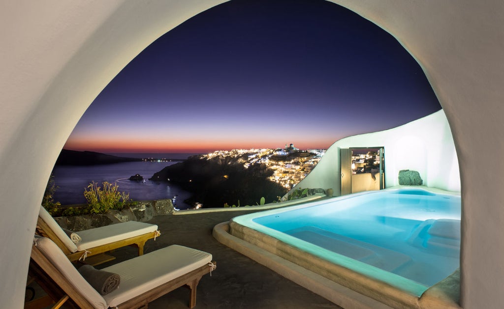 Traditional whitewashed cave houses with curved architecture and infinity pool overlooking Santorini's caldera at sunset, Perivolas Hotel