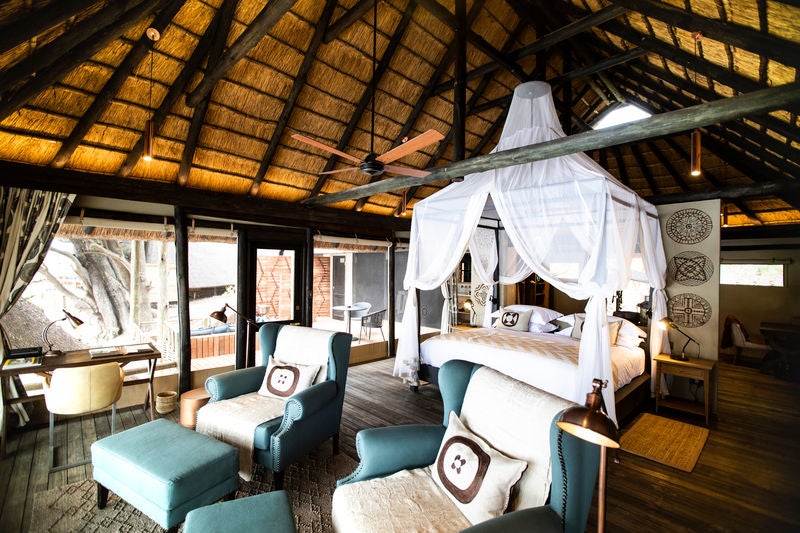 Luxurious safari lodge overlooking a river, featuring tented suites with private decks, plunge pools and panoramic wilderness views