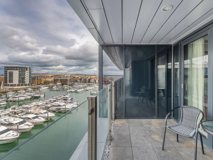 Elegant double room with Juliet balcony overlooking scenic harbour, featuring modern decor, plush bedding, and soft natural lighting in Southampton hotel