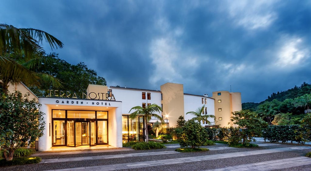 Green-shuttered, elegant colonial facade of Terra Nostra Garden Hotel surrounded by lush botanical gardens and palm trees in Azores, Portugal