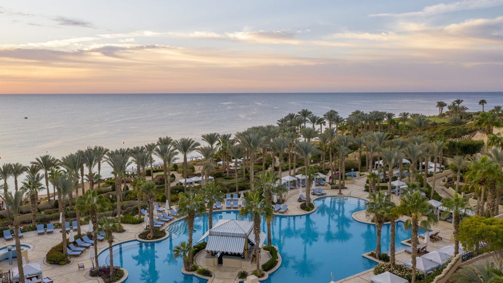 Elegant beachfront resort with infinity pools, palm trees and white Mediterranean-style buildings cascading down to the Red Sea shore