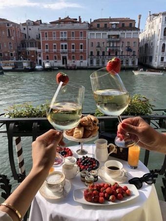 Luxurious historic Venetian palazzo with elegant stone facade, ornate windows, and canal-side setting in warm golden afternoon light