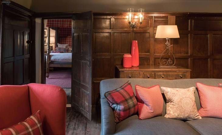 Elegant historic suite with ornate four-poster bed, rich wooden furnishings, and royal blue accents reflecting Charles I era in the renowned Lygon Arms hotel