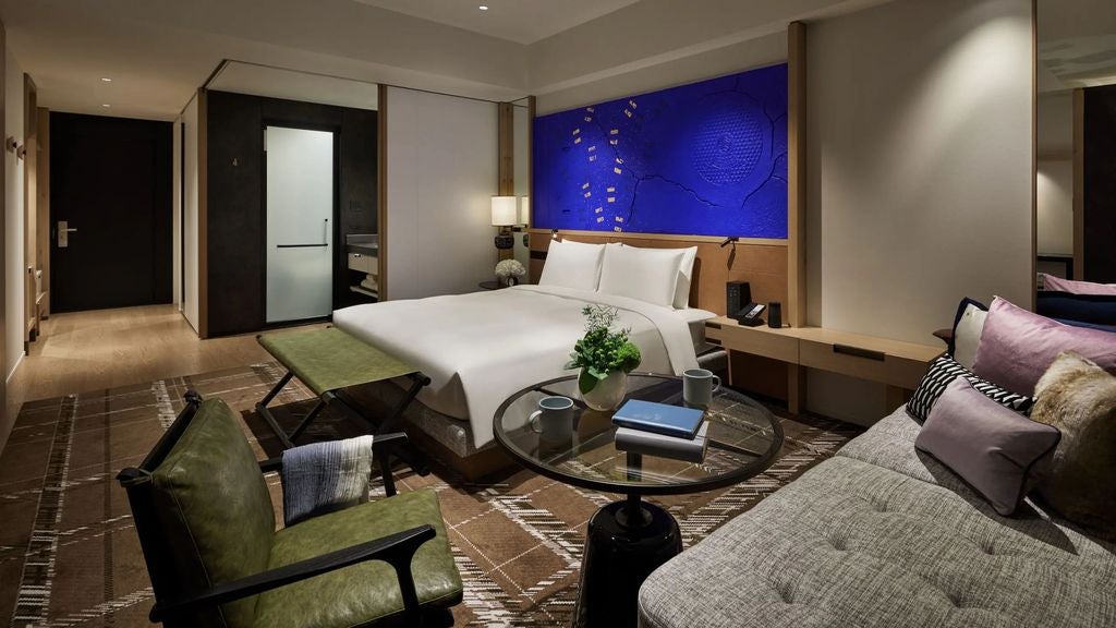 Modern Japanese hotel room with king bed, floor-to-ceiling windows, wooden accents, and city views, featuring stylish minimalist decor