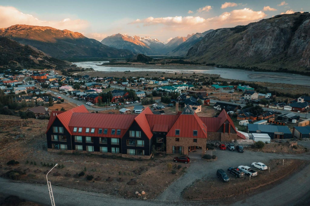 Luxurious mountain retreat with rustic stone architecture, nestled in Andean landscape, featuring elegant outdoor seating and panoramic scenic views of lush scenery