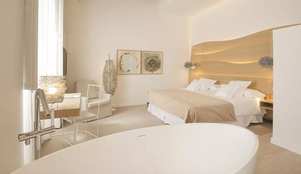 Elegant junior suite at Convent de la Missió with minimalist decor, stone walls, plush white bedding, and warm ambient lighting in a historic Spanish setting